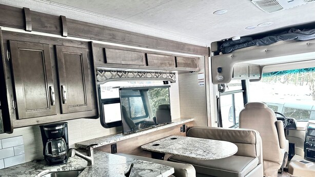 Une cuisine compacte pour camping-car, équipée d’un évier, d’une cuisinière et d’un petit coin repas.