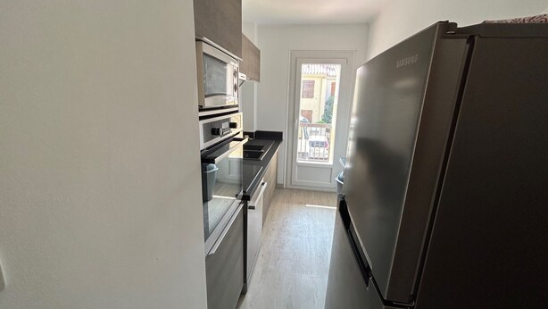 A kitchen with a microwave, oven, and refrigerator.