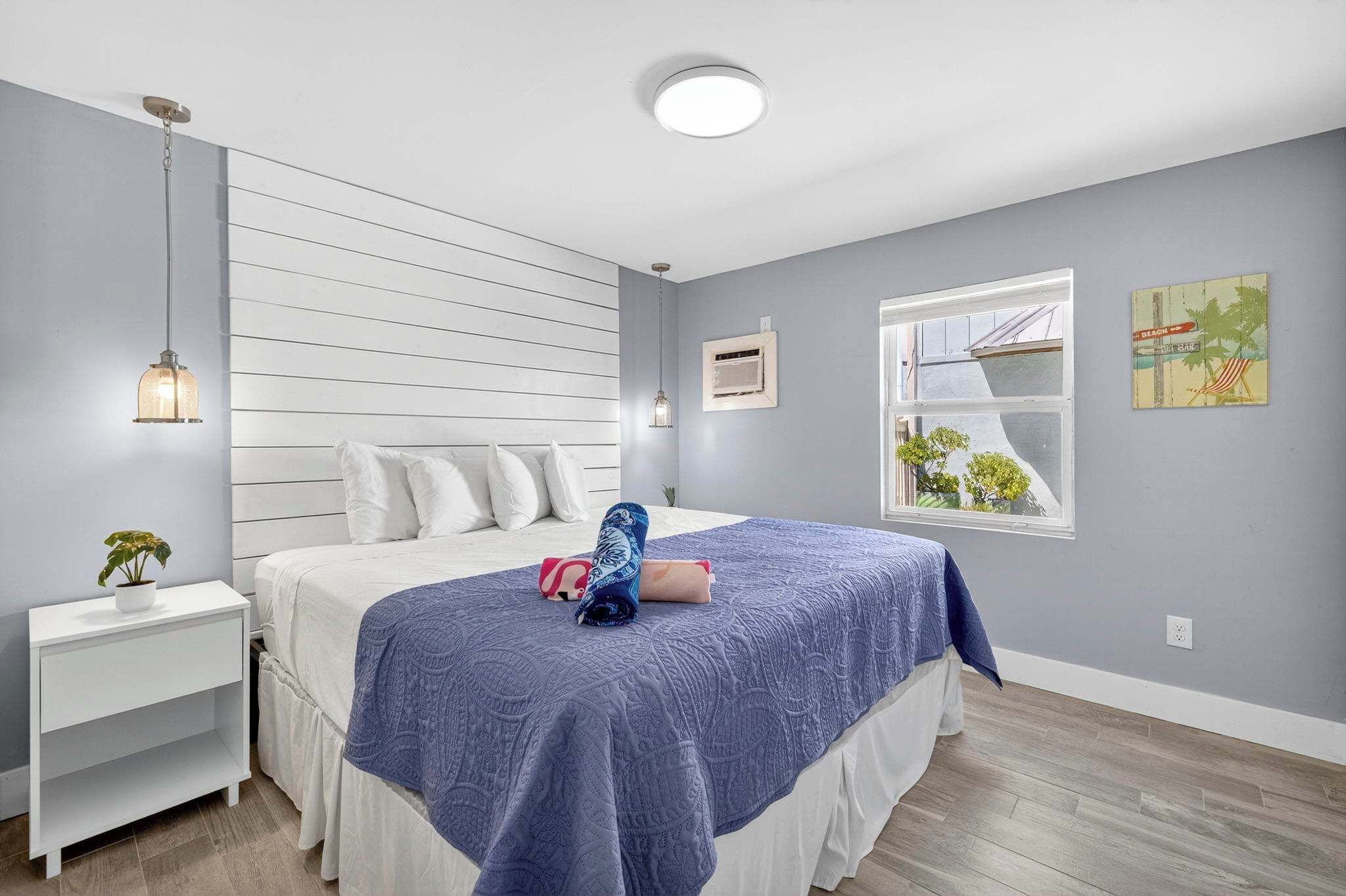 A bedroom with a bed, bedside table, and a window.