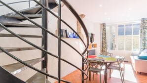 A modern interior with a spiral staircase, a dining area with chairs and a table, and a window with curtains. - Charming duplex with private terrace in the heart of Avranches (Avranches)