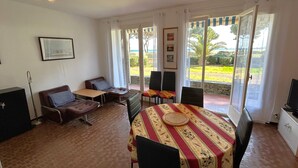 A dining area with a table set for four, surrounded by chairs, a sofa, and a TV. - Apartment for 5 with sea view terrace, 50m to beach (Argelès-sur-Mer)