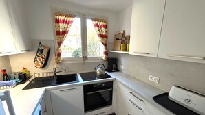 A compact kitchen with white cabinets, a sink, a kettle, and a toaster. - Apartment for 5 with sea view terrace, 50m to beach (Argelès-sur-Mer)
