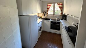 A compact kitchen with a washing machine, a stove, and a sink. - Apartment for 5 with sea view terrace, 50m to beach (Argelès-sur-Mer)