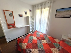Quarto com cama, guarda-roupa, espelho e janela com cortinas.