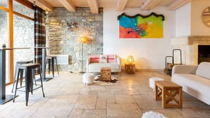 Ein gemütliches Wohnzimmer mit Steinwand, einem farbenfrohen abstrakten Gemälde und einem Kamin.