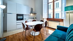 Une cuisine moderne avec des meubles blancs, une table de salle à manger ronde et un canapé bleu.