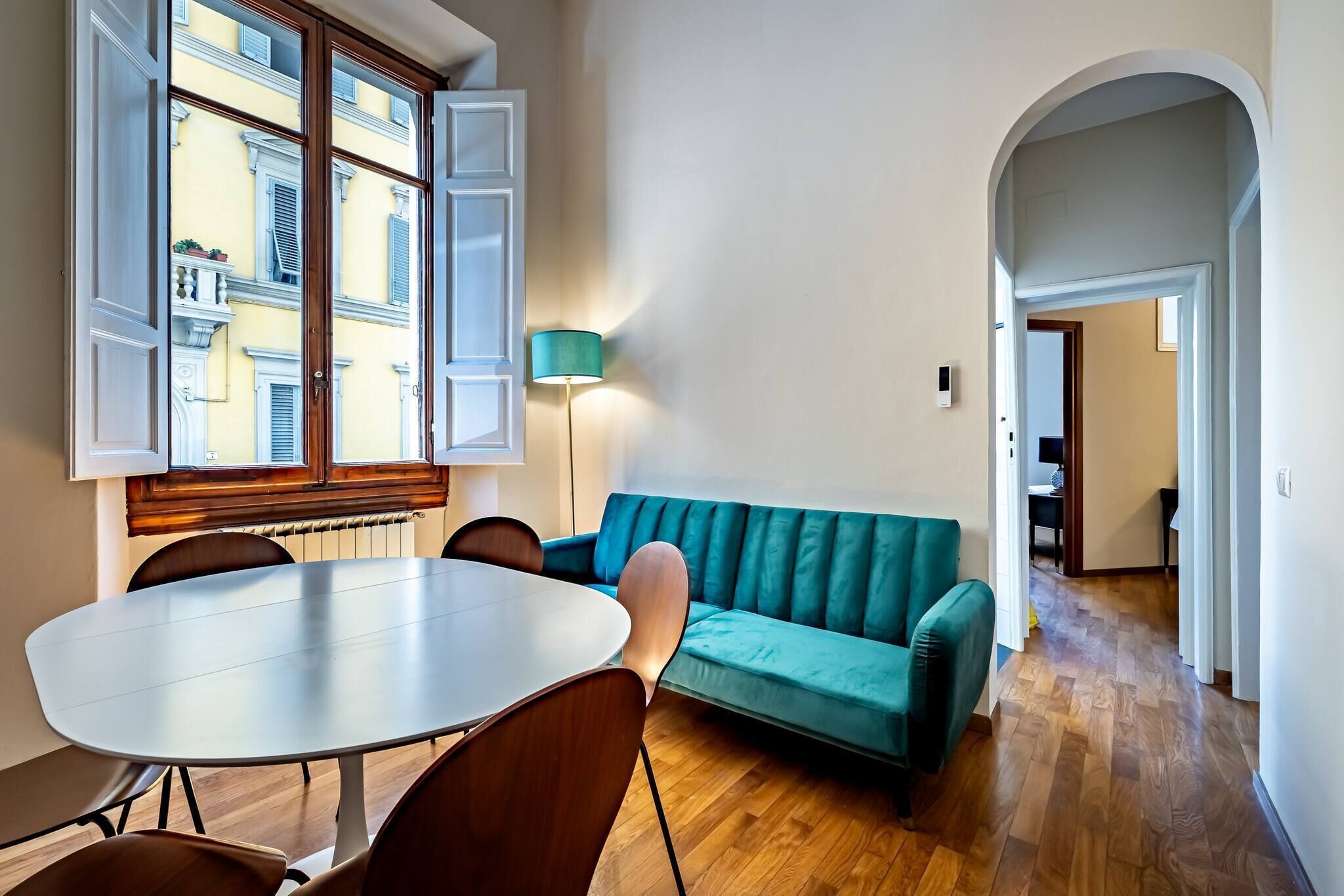 Une pièce comprenant une table à manger, des chaises, un canapé de couleur turquoise et une lampe.