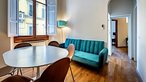 Une pièce comprenant une table à manger, des chaises, un canapé de couleur turquoise et une lampe.