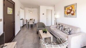 Eine moderne Wohnung mit Essbereich, einem Wohnzimmer mit Sofa und Couchtisch sowie einer Tür mit einem Poster.