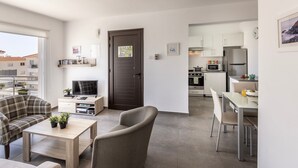 Eine moderne Wohnung mit Wohnzimmer, Essbereich und Küche. Ein Balkon bietet Blick auf die Stadt.