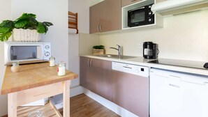 A compact kitchen with a microwave, coffee maker, sink, and cabinets.