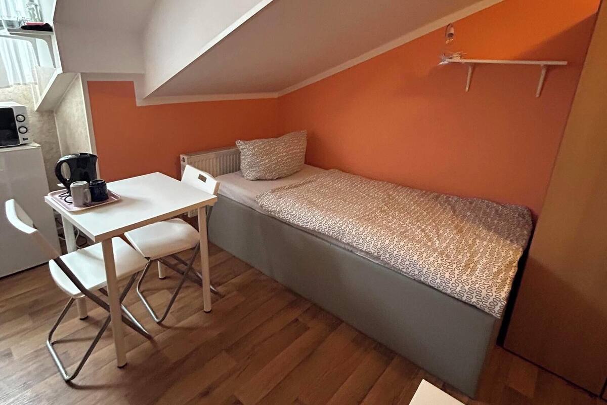 Une pièce de taille modeste, avec un lit en mezzanine, une petite table et une chaise.