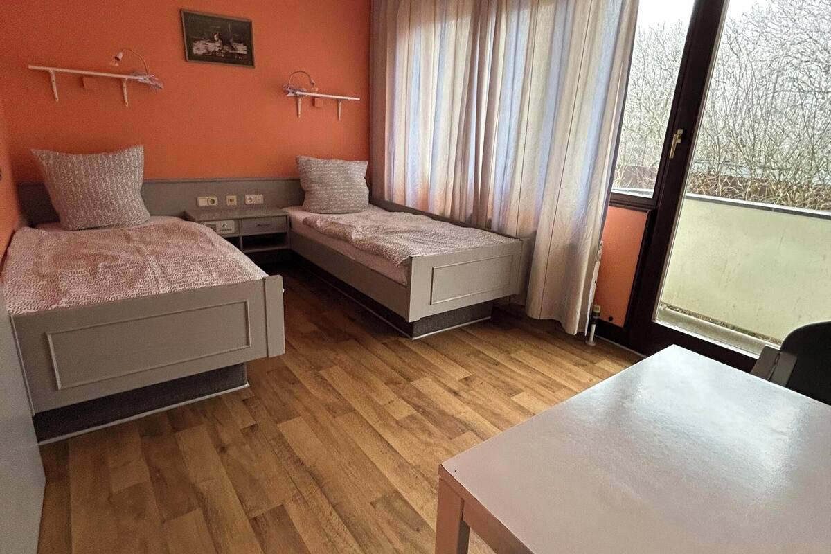 Une chambre avec deux lits simples, une table et une chaise.