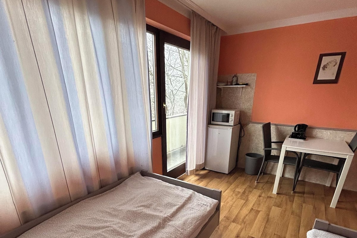 Une pièce de taille modeste comprenant un lit, une petite kitchenette, une table et une chaise.