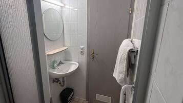 Ein Badezimmer mit rundem Spiegel, Waschbecken und Toilette.