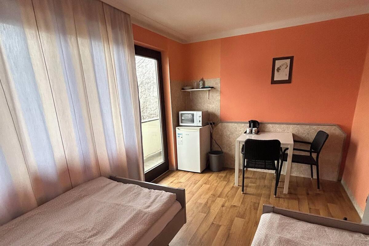 Une petite chambre comprenant un lit, un bureau et une kitchenette.