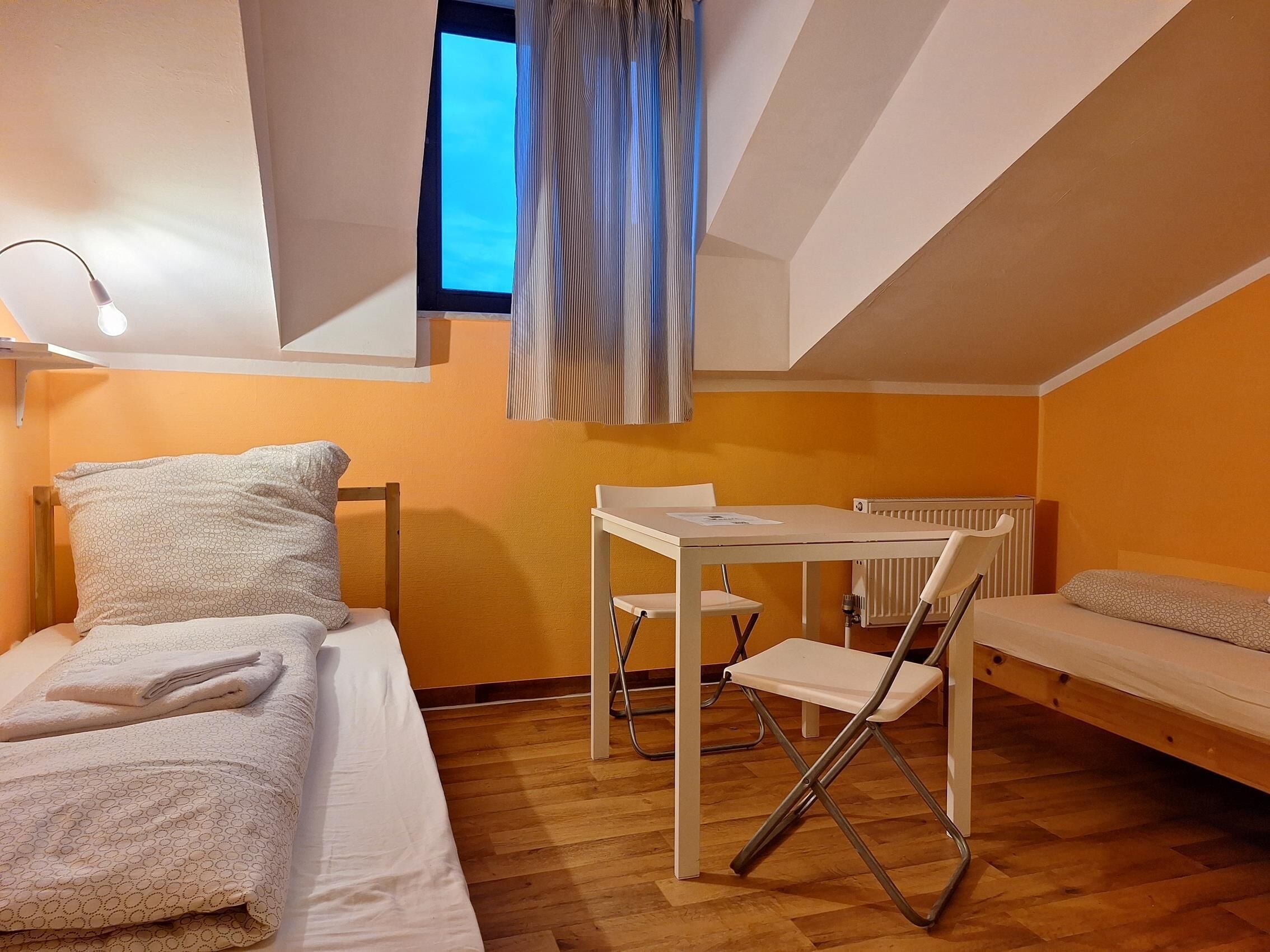 Una habitación pequeña y luminosa con una cama, un escritorio y una silla.