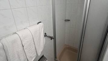 Ein Badezimmer mit Dusche, Toilette und einem Handtuchhalter mit zwei Handtüchern.