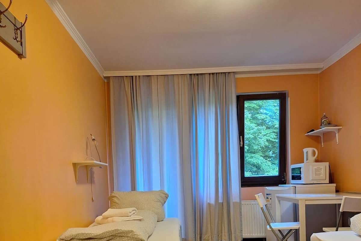 Une petite pièce comprenant un lit, un bureau et une fenêtre.