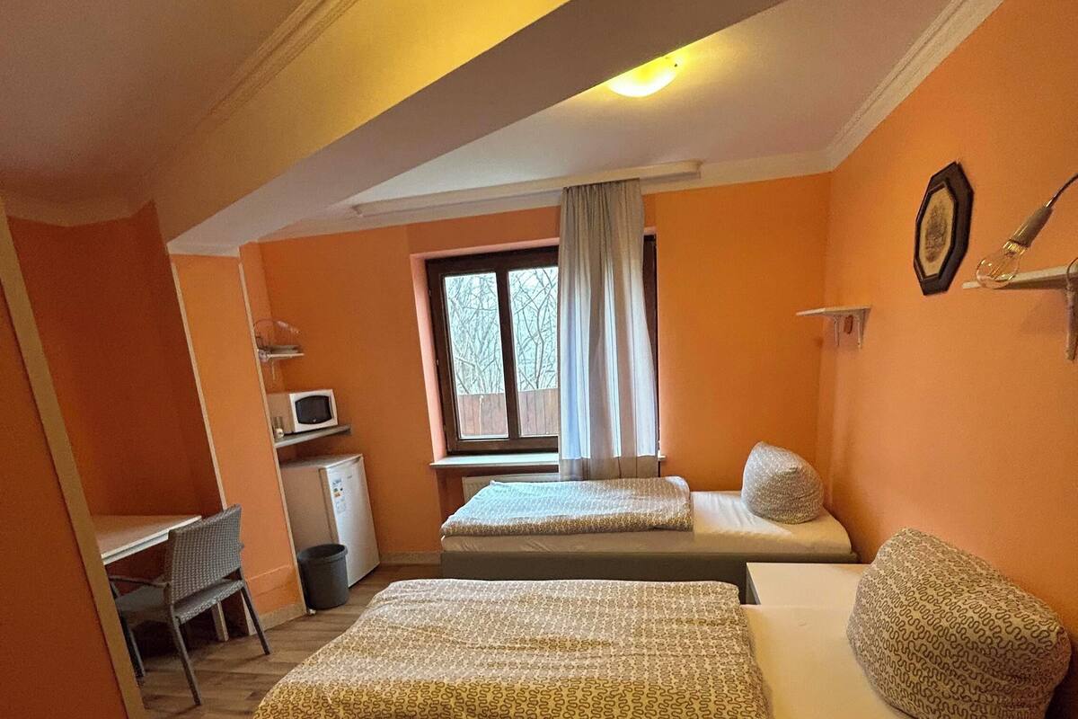 Une chambre avec deux lits, un bureau, une fenêtre et un four à micro-ondes.
