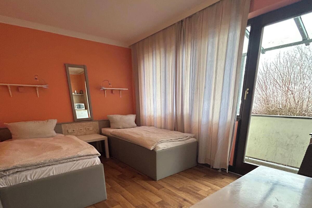 Une chambre d’hôtel avec deux lits, une petite table, un miroir et une vue sur l’extérieur.