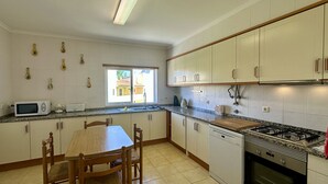 A kitchen with white cabinets, a granite countertop, a microwave, a toaster, a sink, a stove, and a dining table with chairs.