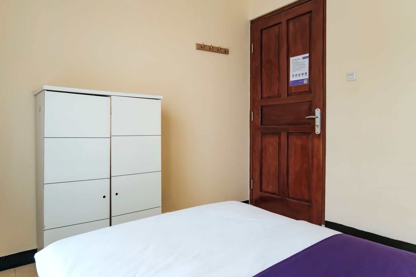 A room with a bed, a wardrobe, and a door.