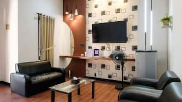 A modern living room with a sofa, a glass coffee table, and a flat-screen TV mounted on the wall.