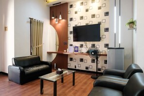 A modern living room with a sofa, a glass coffee table, and a flat-screen TV mounted on the wall. - INNCA Jatidiri Villa, Semarang (Semarang)