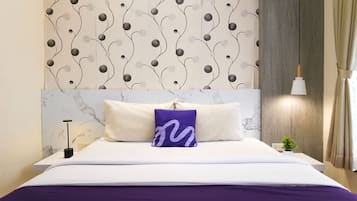 Ein Hotelzimmer mit einem Kopfende mit Marmoroptik, einem Bett mit weißer Bettwäsche und einer violetten Tagesdecke sowie einer Wand mit einem dekorativen Muster.