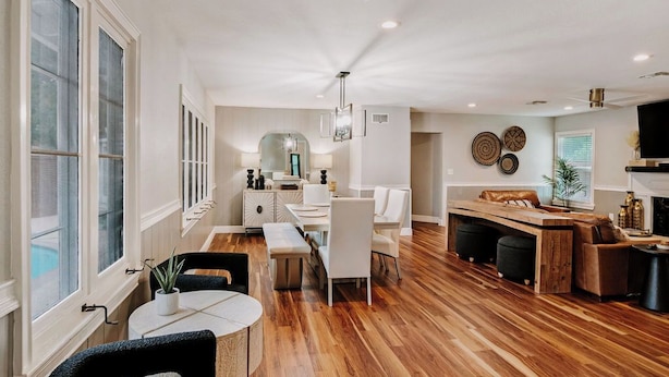 Amplia sala de estar con piso de madera, muebles blancos y un ventanal grande.