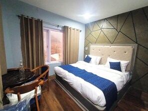 Habitación de hotel con cama, una silla, una mesa y ventana con cortinas.