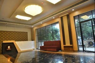 Un vestíbulo con piso de mármol, un sofá rojo, ventanas amplias y un certificado enmarcado en la pared.