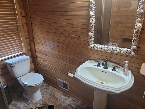 A wooden-paneled bathroom with a toilet, sink, and mirror.