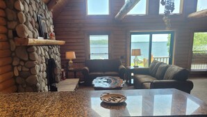 L’intérieur chaleureux d’un chalet avec un mur en pierre, des meubles en bois et une vue sur le lac.