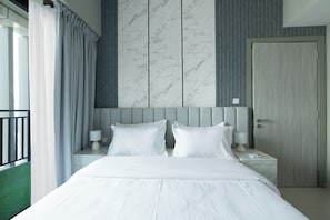 A hotel room with a bed, two bedside tables, a nightstand, a door, and a view of a balcony.