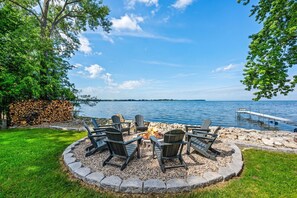 A lakeside patio with Adirondack chairs, a fire pit, and a dock extending into the water. - Sunset Cove| Water Front |Sauna | Hot Tub (Sturgeon Bay)