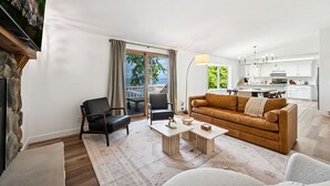 A modern living room with a sofa, chairs, a coffee table, and a fireplace.