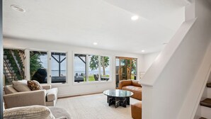 A spacious living room with a large window overlooking a scenic view, a comfortable sofa, a coffee table, and a staircase leading to an upper level.