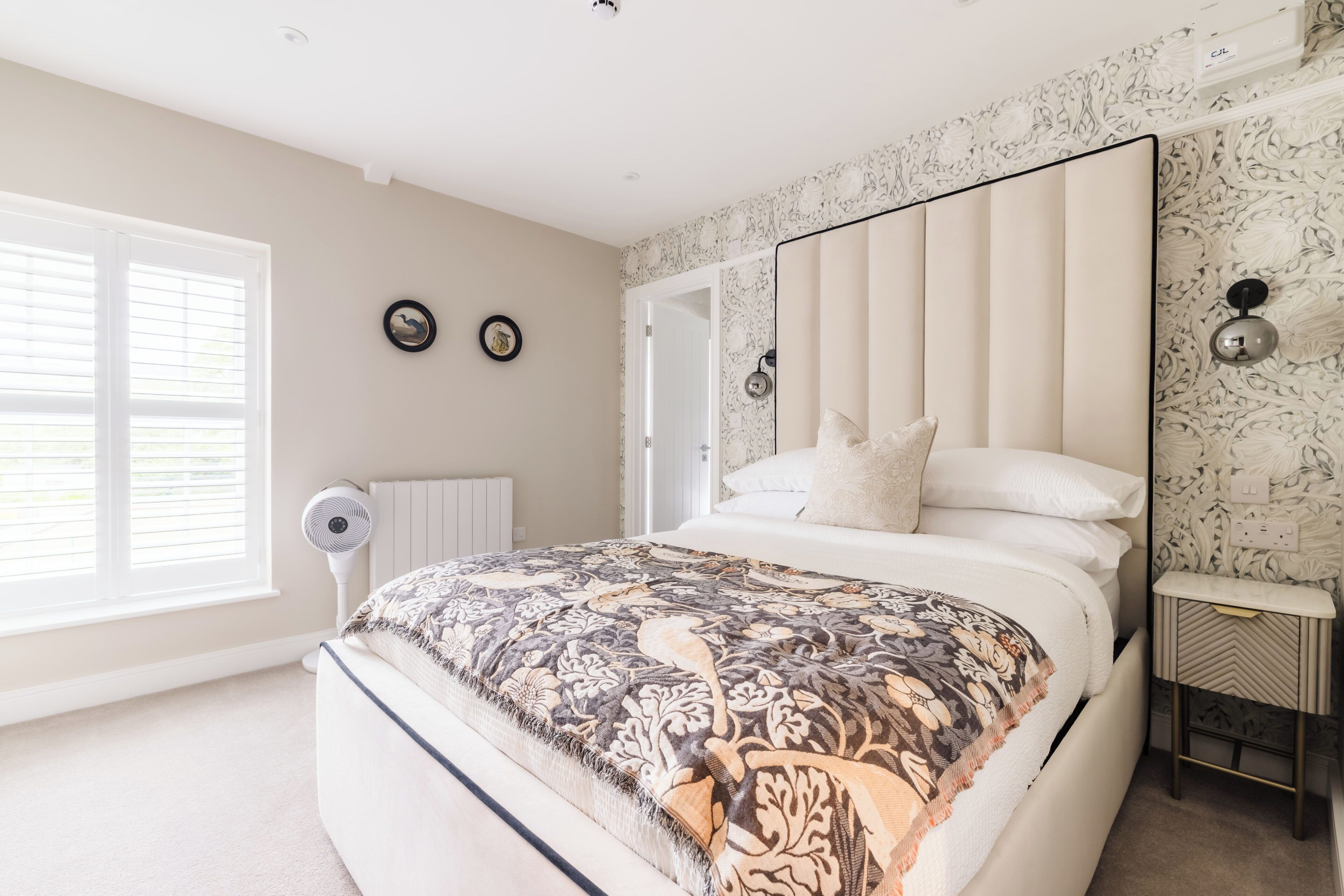 Een slaapkamer met een groot bed, een ventilator, een radiator en een spiegel aan de muur.