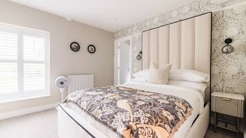 Een slaapkamer met een groot bed, een ventilator, een radiator en een spiegel aan de muur.
