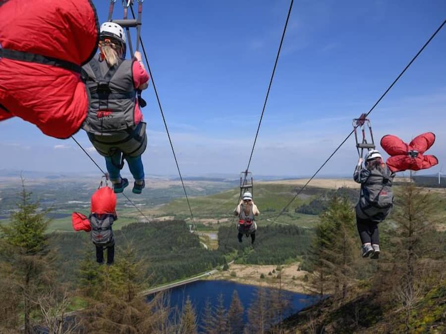 A group of people on a zip line with a scenic landscape in the background.