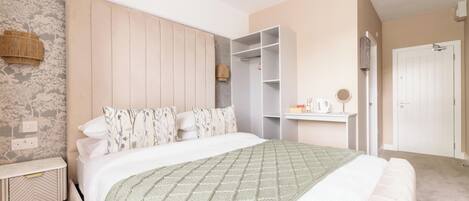 Un dormitorio moderno con una cama grande, una mesita de noche, un armario y un estante empotrado con un hervidor.