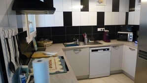 Una cocina moderna con armarios blancos, salpicadero a cuadros blanco y negro, electrodomésticos de acero inoxidable y lavavajillas.