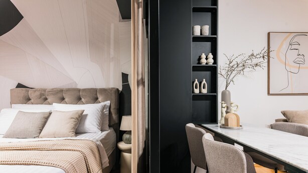 Un dormitorio moderno con una cama grande, mesitas de noche, un escritorio y una silla.