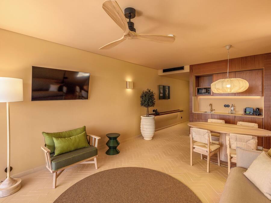 A modern living room with a sofa, a dining table, and a ceiling fan.