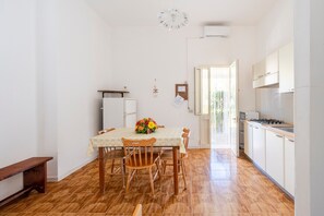 A kitchen with a dining table, chairs, a refrigerator, and a stove.