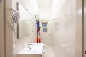 Ein modernes Badezimmer mit einem weißen Waschbecken, einer Toilette und einer Duschkabine.