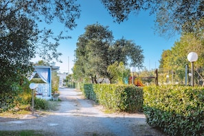 A pathway leading to a building with a blue facade, surrounded by greenery and a clear sky. - Bungalow 'Agriturismo Alimini-  1' with Private Terrace, Wi-Fi and Air Conditioning (frassanito)