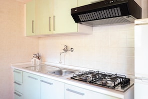 A kitchen with a gas stove, sink, and light green cabinets.